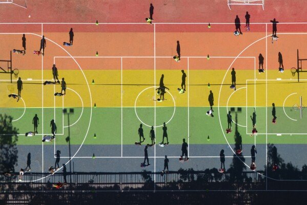 Children cast shadows on a basketball court during a sports workshop at a park in Santiago, Chile, on Feb. 18, 2025. (AP Photo/Matias Basualdo)