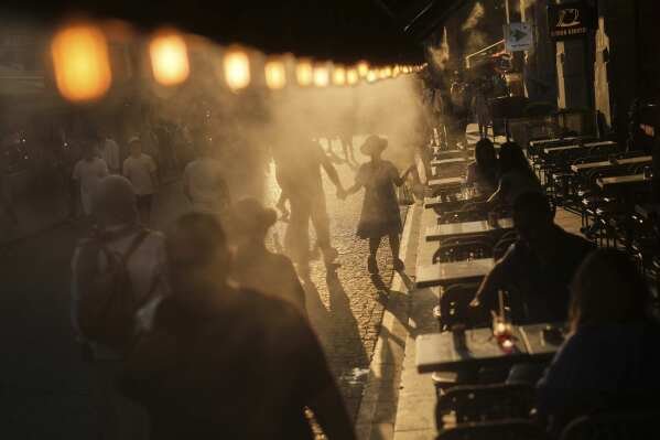 A coffee bar in Istanbul sprays mist to cool people passing by on July 24, 2025. (AP Photo/Francisco Seco)