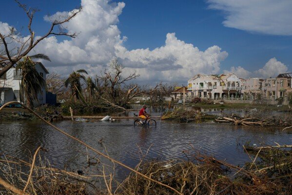 A man rides his bicycle in the aftermath of Hurricane Melissa on Oct. 30, 2025, in Black River, Jamaica. (AP Photo/Matias Delacroix)
