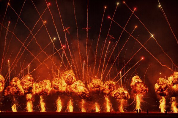 The Air Bandits aerobatic team, led by Lithuanian pilot Jurgis Kairys, performs above a pyrotechnics display at the Aurel Vlaicu International Airport during the Bucharest International Air Show in Bucharest, Romania, Aug. 30, 2025. (AP Photo/Andreea Alexandru)