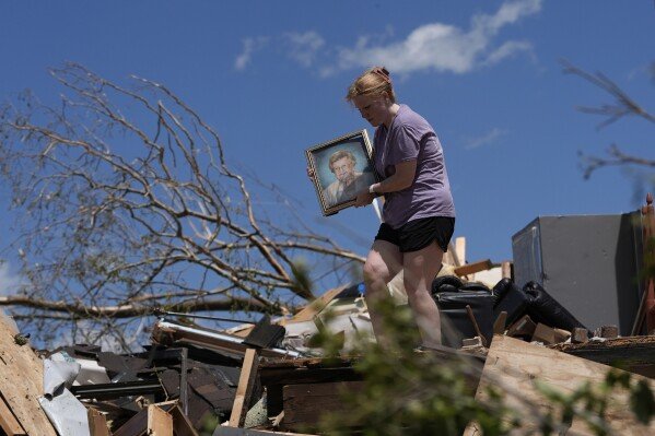 Hailee Allen saves a family picture from Lynn and Don White's home on May 17, 2025, after a deadly tornado tore through London, Ky. (AP Photo/Carolyn Kaster)