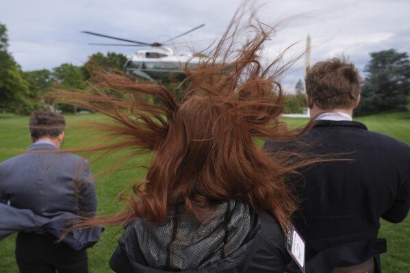 People watch as Marine One, with President Donald Trump aboard, departs the White House in Washington en route to the Trump National Golf Club Washington D.C. for a crypto dinner on May 22, 2025. (AP Photo/Jacquelyn Martin)