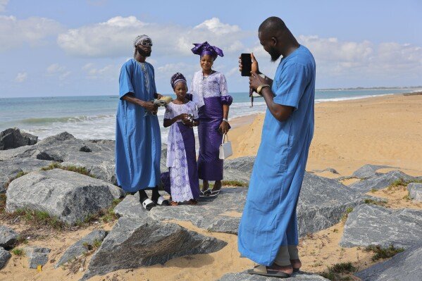 A family poses for a photo after Eid al-Adha prayers on June 6, 2025, on a beach in Keta, Ghana. (AP Photo/Misper Apawu)