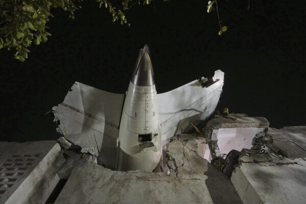 The tail of an airplane sticks out of a building where it crashed in Ahmedabad, India, on June 12, 2025. (AP Photo/Ajit Solanki)