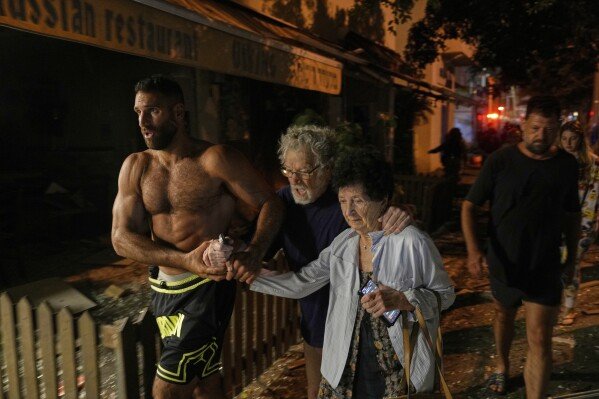 People evacuate after a missile launched from Iran struck Tel Aviv, Israel, on June 16, 2025. (AP Photo/Baz Ratner)