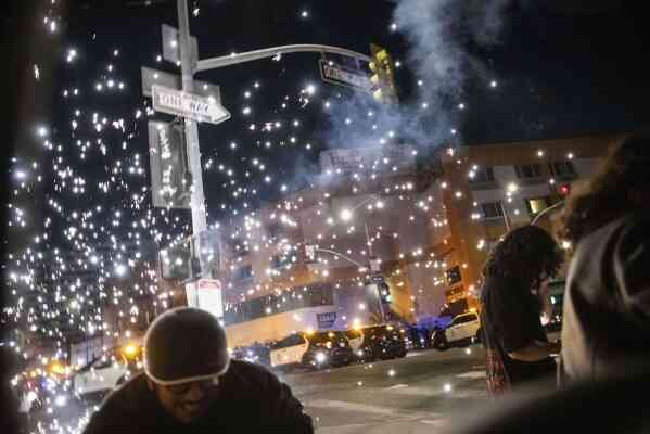 People take cover as a firework explodes during a protest near the Metropolitan Detention Center in downtown Los Angeles, June 8, 2025. (AP Photo/Ethan Swope)