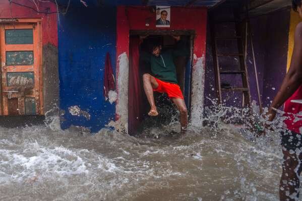 A man jumps as waves lash his house during high tide on the shore of the Arabian Sea in Mumbai, India, on June 25, 2025. (AP Photo/Rafiq Maqbool)