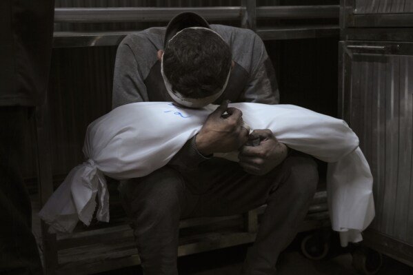 Hossam Azzam holds the body of his child, Amir, who was killed in an Israeli airstrike on Gaza, at Shifa Hospital in Gaza City, on July 15, 2025. (AP Photo/Jehad Alshrafi)
