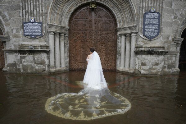Bride Jamaica Aguilar prepares to enter the flooded Barasoain church for her wedding in Malolos, Bulacan province, Philippines, on July 22, 2025. (AP Photo/Aaron Favila)