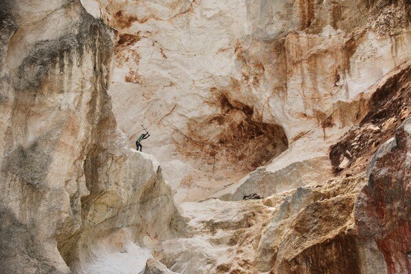 A worker pounds into rock to make gravel and sand in Kenscoff, a neighborhood of Port-au-Prince, Haiti, on July 24, 2025. (AP Photo/Odelyn Joseph)