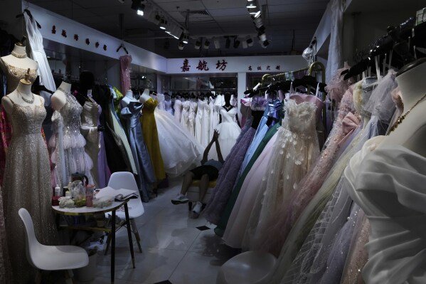 Dresses hang at a garment store in Beijing on July 27, 2025. (AP Photo/Mahesh Kumar A.)