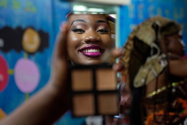 A model applying makeup is reflected in a mirror during the Mr. and Mrs. Kibera leadership contest held on International Youth Day in Nairobi, Kenya, on Aug. 12, 2025. (AP Photo/Brian Inganga)