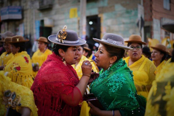 A supporter of presidential candidate Samuel Doria Medina applies lipstick on another at a campaign rally in La Paz, Bolivia, on Aug. 12, 2025, five days ahead of presidential elections. (AP Photo/Natacha Pisarenko)