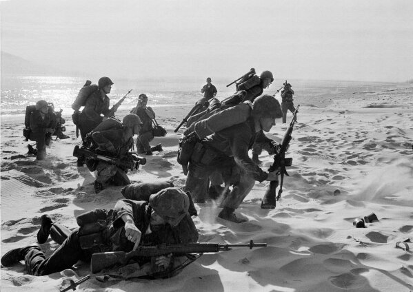 FILE - Newly-landed U.S. Marines make their way through the sands of Red Beach at Da Nang, Vietnam, on their way to reinforce the air base as South Vietnamese Rangers battled guerrillas several miles south of the beach, April 10, 1965. (AP Photo/Peter Arnett, File)
