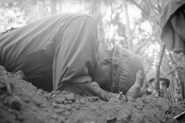 FILE - A paratrooper of the U.S. 173rd Airborne Brigade clutches his helmet as he takes cover during a North Vietnamese mortar attack in Vietnam, Nov. 21, 1967. (AP Photo/Peter Arnett, File)
