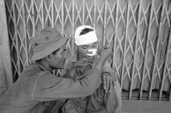 FILE - A South Vietnamese army medic feeds a wounded North Vietnamese prisoner in Xuan Loc, Vietnam, April 13, 1975. (AP Photo/Peter Arnett, File)