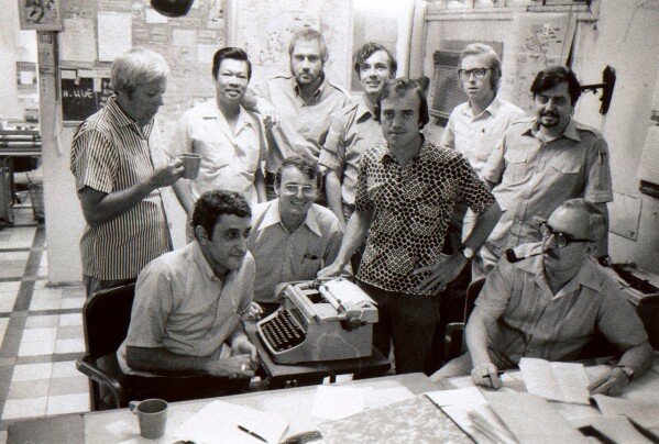 FILE - Associated Press correspondent Peter Arnett, front center right, poses for a photo with other AP staff members at the AP Saigon bureau in Vietnam, April 18, 1972. The staff includes, front row from left, George Esper, Carl Robinson, Arnett, and Ed White and back row, from left, Hugh Mulligan, chief Vietnamese reporter Huynh Minh Trinh, Holger Jensen, Richard Blystone, Max Nash and Richard Pyle. (AP Photo, File)