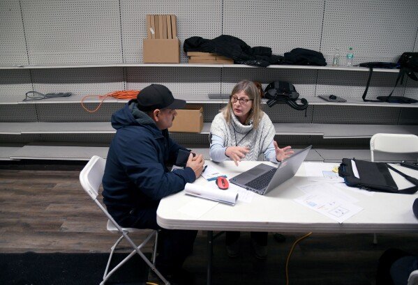 Amela Lipnicevic with the Nebraska Department of Labor, right, helps Tyson Foods employee Guillermo Vargas during an informational meeting in Lexington, Neb., Wednesday, Dec. 3, 2025. (AP Photo/Thomas Peipert)