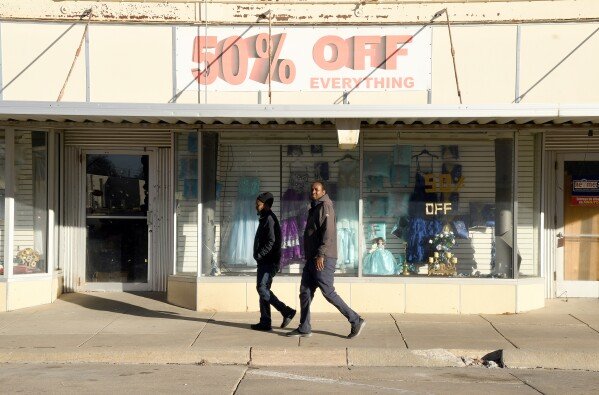 Two men walk past a business in downtown Lexington, Neb., Saturday, Dec. 6, 2025. (AP Photo/Thomas Peipert)