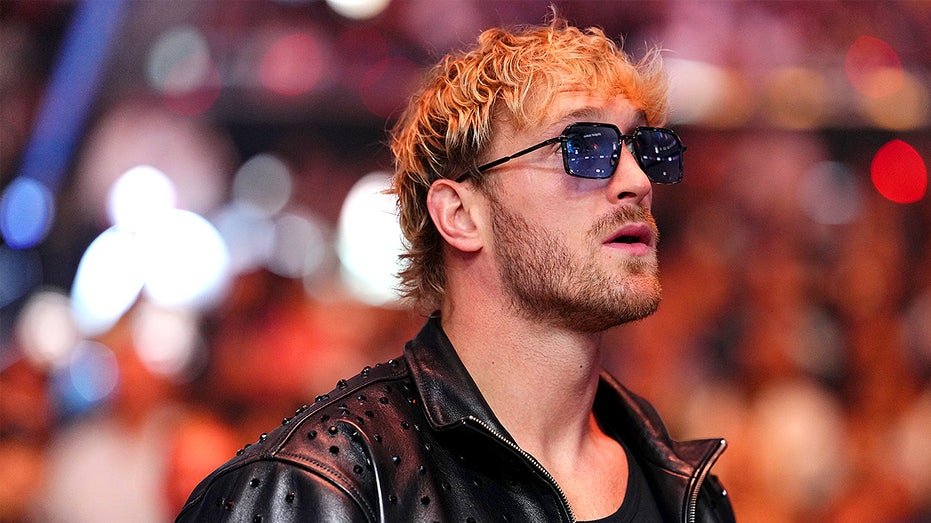 Logan Paul stands at ringside while attending a boxing championship event inside a stadium.