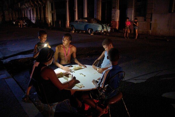 People play dominoes outdoors during a blackout in Havana, Sept. 10, 2025. (AP Photo/Ramon Espinosa, File)