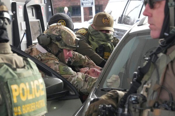 U.S. Border Patrol agents remove a person from their vehicle, Sunday, Jan. 11, 2026, in St. Paul, Minn. (AP Photo/Adam Gray)