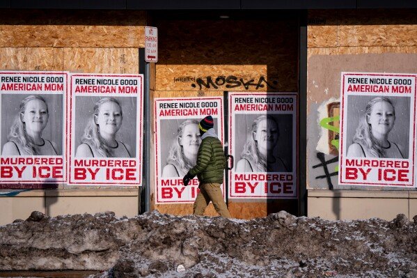 A person walks past signage for Renee Good, who was fatally shot by an ICE officer earlier in the week, in Minneapolis, Minn., Sunday, Jan. 11, 2026. (Christopher Katsarov/The Canadian Press via AP)