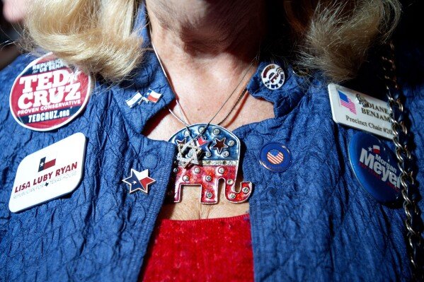 FILE - Diane Benjamin, a Dallas precinct chairman, sports campaign buttons and Republican themed jewelry during the Dallas County Republican Party election night watch party, Nov. 6, 2018 at The Statler Hotel in Dallas. (AP Photo/Jeffrey McWhorter)