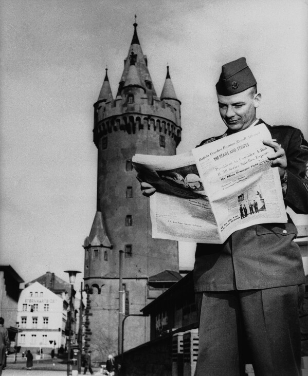 A GI reads a recent edition of The Stars & Stripes in front of Eschenheimer Tower in Frankfurt, West Germany, April 24, 1967. (AP Photo)