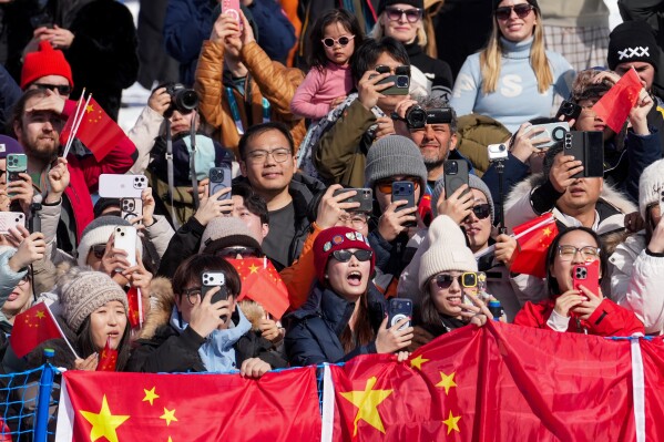 Fans celebrate after gold medalist China's Eileen Gu won the women's freestyle skiing halfpipe final at the 2026 Winter Olympics, in Livigno, Italy, Sunday, Feb. 22, 2026. (AP Photo/Lindsey Wasson)