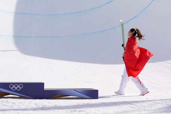 Gold medalist China's Eileen Gu walks to the podium after winning the women's freestyle skiing halfpipe final at the 2026 Winter Olympics, in Livigno, Italy, Sunday, Feb. 22, 2026. (AP Photo/Abbie Parr)
