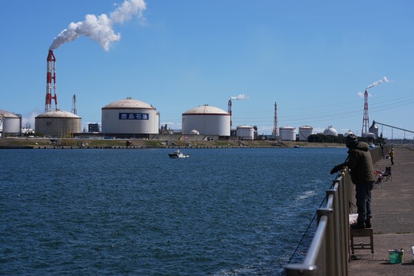 Part of Eneos group's Kashima oil refinery is seen as local residents try to catch fish at a wharf in Kamisu, east of Tokyo, Sunday, March 15, 2026.(AP Photo/Hiro Komae)
