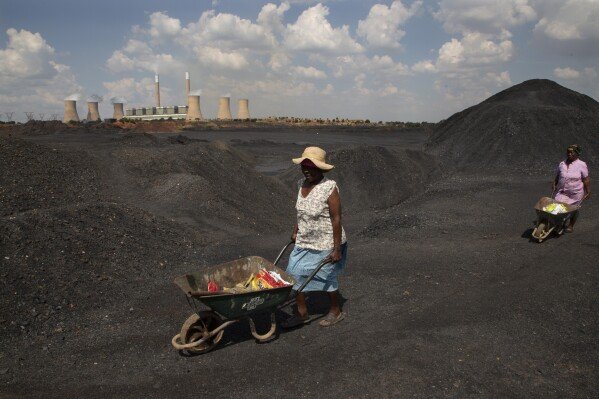 FILE - Women push wheelbarrows atop a coal mine dump at the coal-powered Duvha power station, near Emalahleni east of Johannesburg, Nov. 17, 2022. Humanity still has a chance, close to the last one, to prevent the worst of climate change’s future harms, a top United Nations panel of scientists said Monday, March 20, 2023. But doing so requires quickly slashing carbon pollution and fossil fuel use. (AP Photo/Denis Farrell, File)