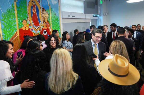 Washington Gov. Bob Ferguson, center right, talks with attendees after signing a bill limiting facial coverings on law enforcement officers, Thursday, March 19, 2026, in Seattle. (AP Photo/Lindsey Wasson)
