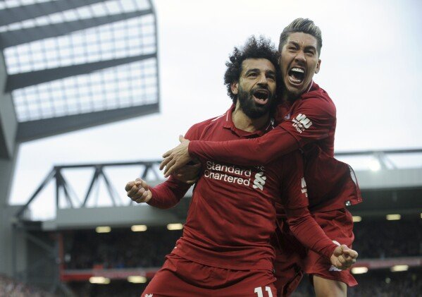 Liverpool's Mohamed Salah, left, and Liverpool's Roberto Firmino celebrate after Tottenham's Toby Alderweireld scores an own goal past his goalkeeper during the English Premier League soccer match between Liverpool and Tottenham Hotspur at Anfield stadium in Liverpool, England, March 31, 2019. (AP Photo/Rui Vieira, File)
