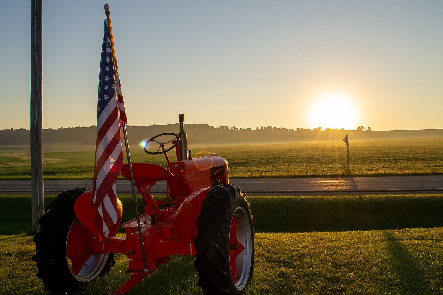 Closeup of a patriotic international Farmall tractor with the US flag at sunrise