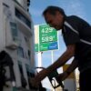 Carlos Ferre holds a gas pump nozzle as he stands near a gas pump at a gas station in Miami on April 6. Behind him is a tall sign that says regular gasoline is $4.29 and diesel is $5.89.