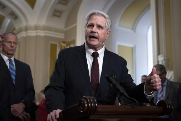 Sen. John Hoeven, R-N.D., center, accompanied by Senate Majority Leader Sen. John Thune, R-S.D., left, speaks to reporters after a Senate policy luncheon, at the Capitol in Washington, Feb. 25, 2025. (AP Photo/Ben Curtis, File)