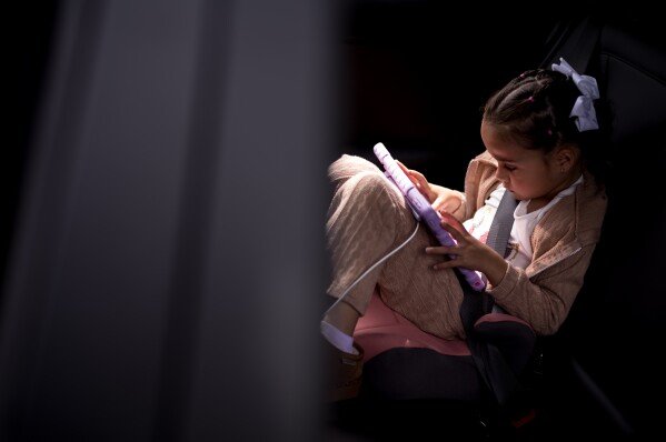 Milena Faria, whose mother, Dr. Rubeliz Bolivar, is in immigration custody, sits in a car while waiting for her father, Milenko, outside the U.S. Citizenship and Immigration Services facility in Tustin, Calif., Thursday, April 16, 2026. (AP Photo/Jae C. Hong)