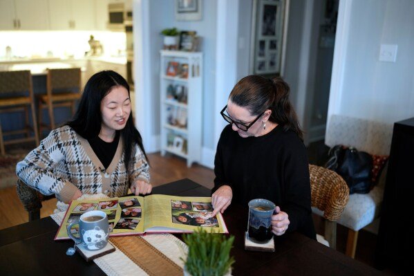 Zoie Albers and her mother Leslie Albers, right, look through family photographs at their home Saturday, Jan. 17, 2026, in Piperton, Tenn. (AP Photo/George Walker IV)