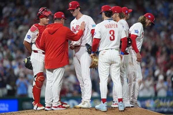 Philadelphia Phillies manager Rob Thomson, second from left, releases pitcher Andrew Painter, center, during the sixth inning of a baseball game against the Washington Nationals, March 31, 2026, in Philadelphia. (AP Photo/Matt Rourke, File)