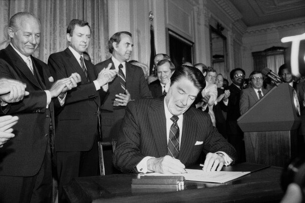 FILE - In a June 30, 1982 file photo, President Ronald Reagan signs an expansion of the 1965 Voting Rights Bill during a ceremony in  the East Room of the White House. The Justice Department will sue the state of North Carolina for alleged racial discrimination over tough new voting rules, the latest effort by the Obama administration to fight back against a Supreme Court decision that struck down the most powerful part of the landmark Voting Rights Act and freed southern states from strict federal oversight of their elections. North Carolina has a new law scaling back the period for early voting and imposing stringent voter identification requirements. It is among at least five Southern states adopting stricter voter ID and other election laws.  (AP Photo, File)