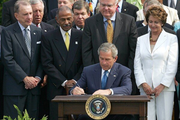 This July 27, 2006 file photo shows President George W. Bush, center, surrounded by members of Congress signing legislation extending for 25 years the Voting Rights Act, on the South Lawn at the White House in Washington. (AP Photo/Ron Edmonds, File)  