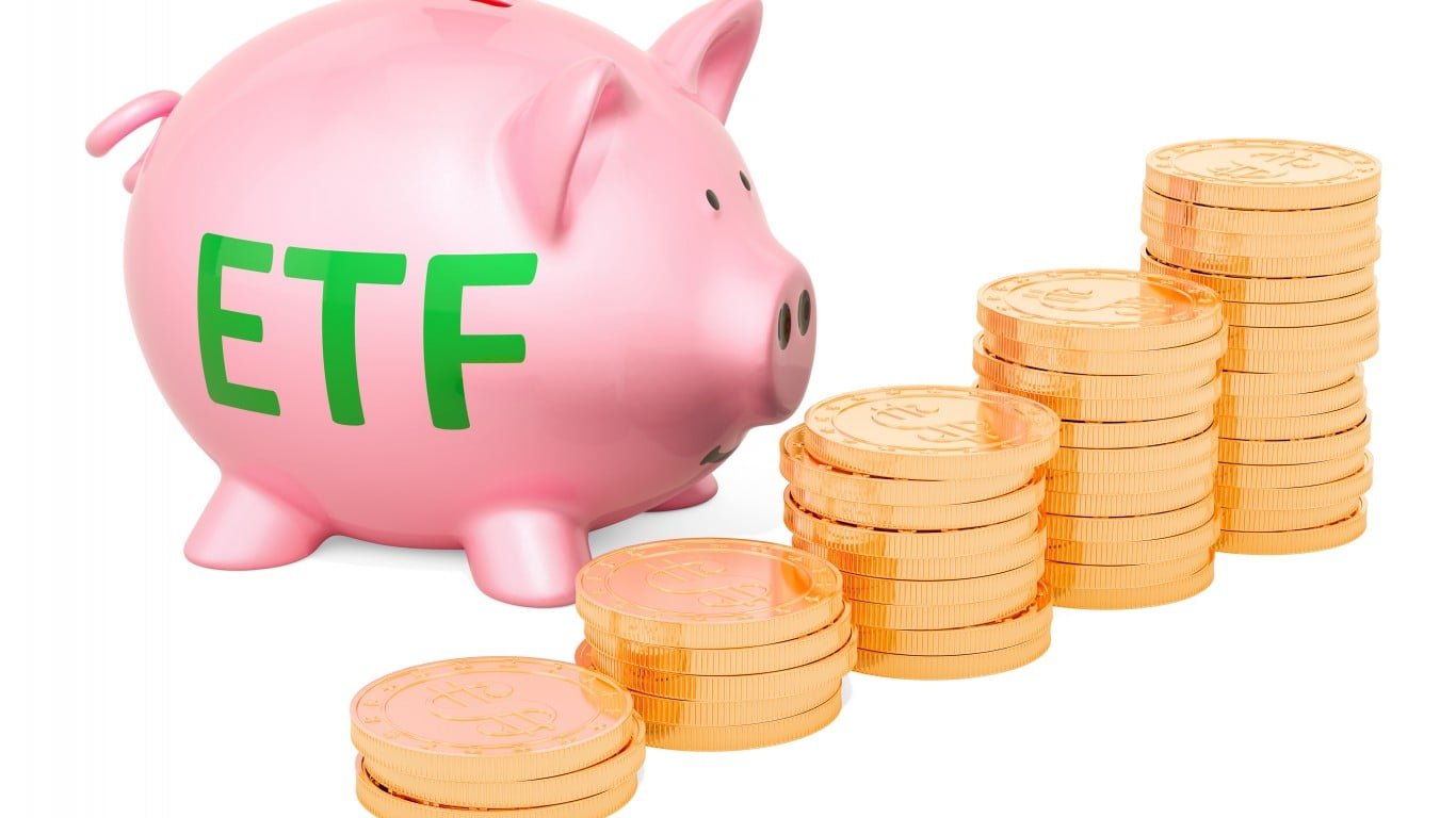 A pink piggy bank with 'ETF' in green letters on its side is positioned next to several ascending stacks of golden coins, representing financial growth. The stacks of coins progressively get taller from left to right on a white background.