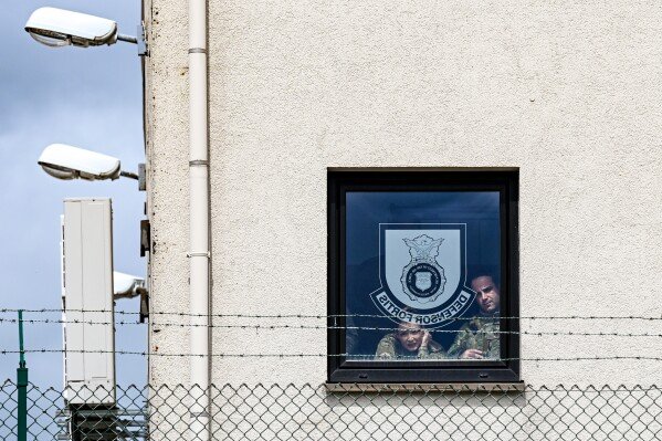 U.S. Air Force Airmen watch from a window as U.S. Vice President JD Vance disembarks Air Force Two upon his arrival at Ramstein Air Base, Germany, Thursday, April 24, 2025. (Kenny Holston/Pool Photo via AP)