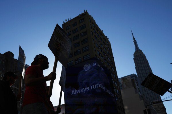 Long Island Rail Road workers are silhouetted as they walk on the picket line outside of Penn Station on the first day of their strike, Saturday, May 16, 2026, in New York. (AP Photo/Heather Khalifa)