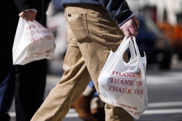 Pedestrians carry plastic bags in Philadelphia, March 3, 2021. (AP Photo/Matt Rourke)