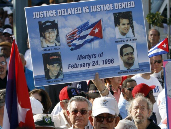 Mario de la Pena carries a poster with the photos of the four pilots shot down by Cuban Migs, his son Mario de la Pena, top right, was among the pilots, during a freedom for Cuba march in Miami, Thursday, Feb. 24, 2011.  (AP Photo/Alan Diaz)