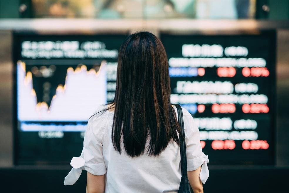 Woman looking at a stock exchange board wondering what the last half of 2026 may end like.