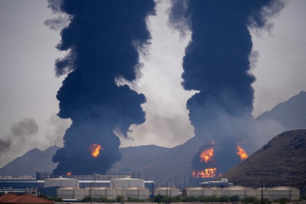 Plumes of smoke and fire rise after debris from an intercepted Iranian drone struck an oil facility, according to authorities, in Fujairah, United Arab Emirates, March 14, 2026. (AP Photo/Altaf Qadri, File)